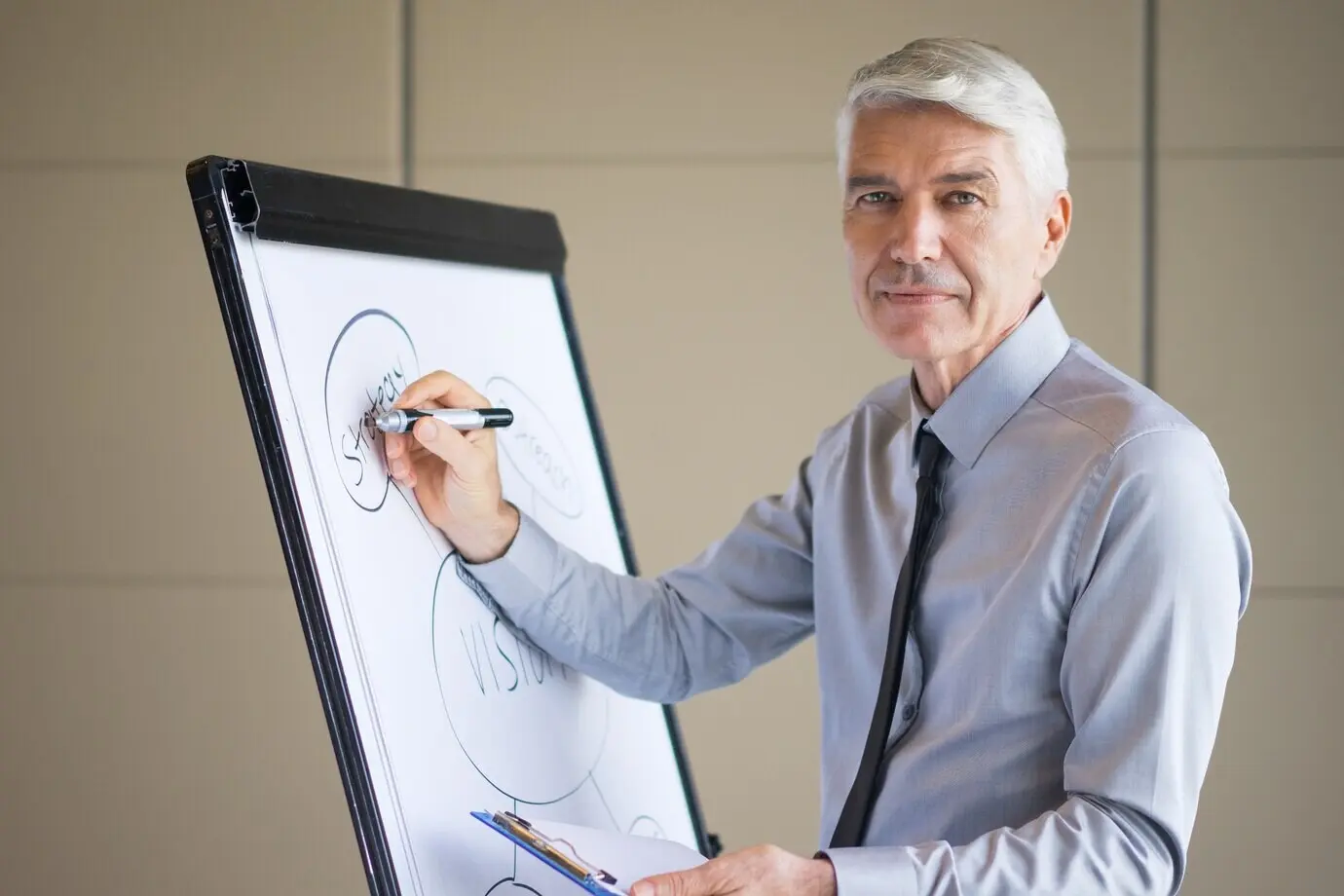 Zufriedener erfahrener Hochschuldozent zeichnet ein Geschäftsdiagramm