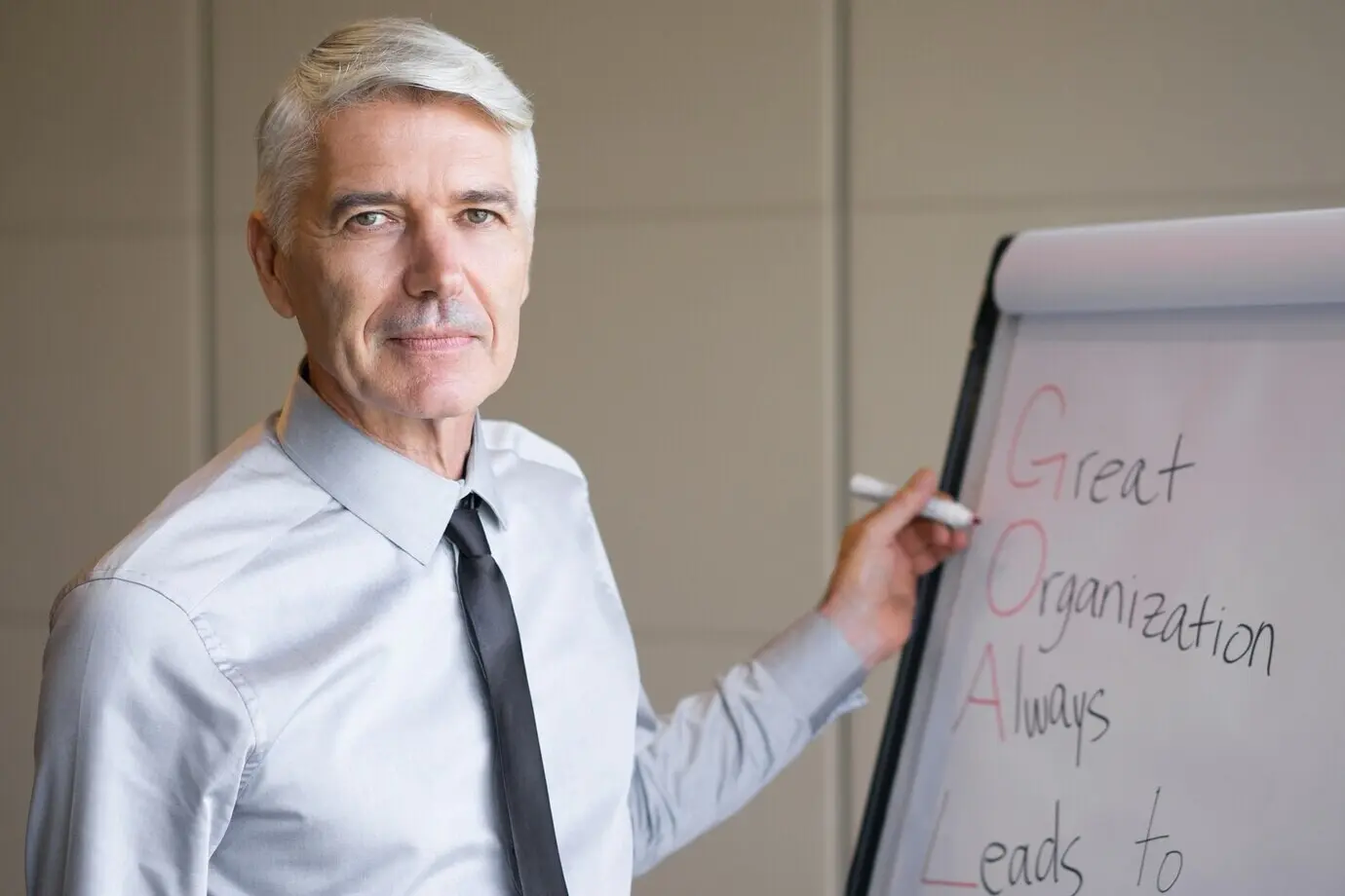 Ernster älterer Redner schreibt auf einem Flipchart.